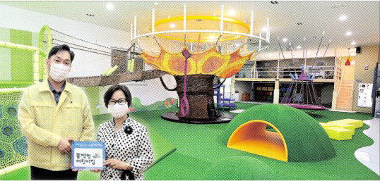 지난달 31일 서울 동작구청 기획상황실에서 이창우(왼쪽) 동작구청장이 동작형어린이집 공인증서를 전달한 뒤 기념사진을 찍고 있다. 사당3동에 있는 맘스하트카페의 실내 놀이터 사진을 합성했다. 동작구 제공