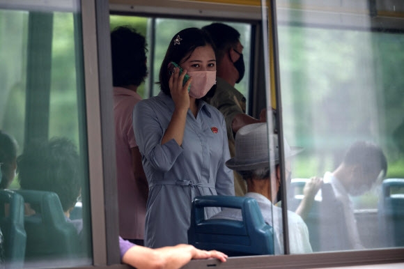 13일 북한 평양에서 버스를 탄 여성이 마스크를 쓴 채 휴대폰으로 통화를 하고 있다. AFP 연합뉴스