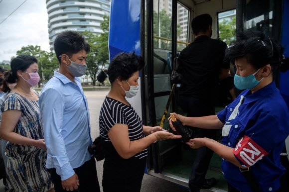북한 평양 시민들이 13일 버스에 타기 전 코로나19 예방책으로 손소독제를 받고 있다. AFP 연합뉴스