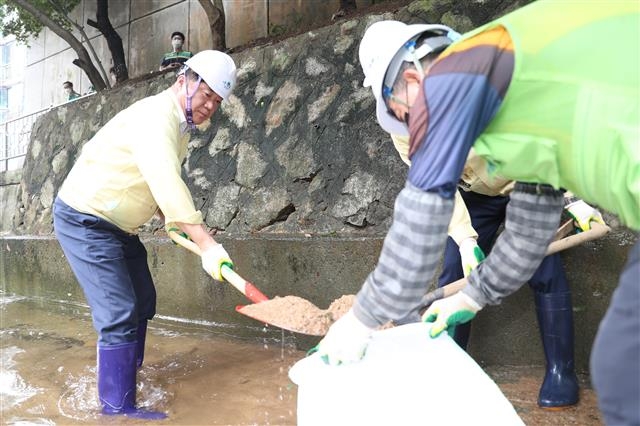 박준희(왼쪽) 서울 관악구청장이 지난 12일 인헌동의 한 산사태 취약지역을 찾아 삽을 들고 빗물에 휩쓸려 내려온 토사를 걷어내고 있다. 관악구 제공