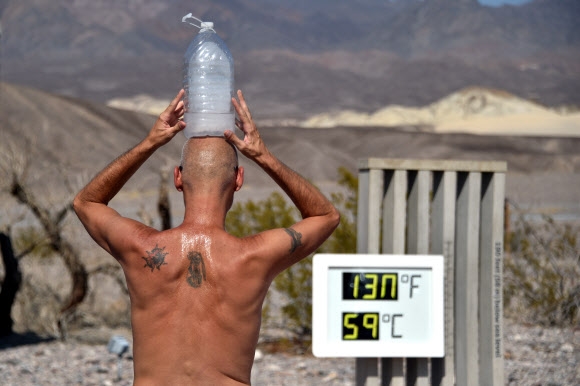 한 남성이 17일(현지시간) 미국 캘리포니아주 데스밸리의 퍼니스 크릭 방문객 센터에서 온도계가 화씨 130도를 기록한 가운데, 머리에 얼린 물병을 얹고 더위를 식히고 있다. 로이터 연합뉴스