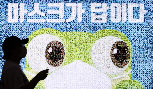 ‘마스크가 답이다’라고 쓴 경기도 수원역의 한 광고판 앞을 한 시민이 지나가고 있다. 연합뉴스