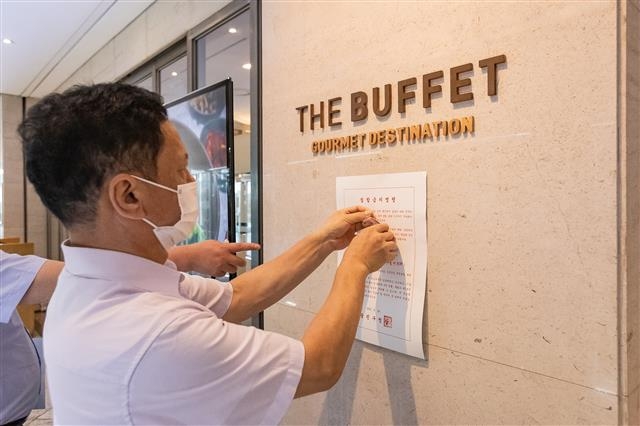 서울 광진구 관계자가 지난 19일 지역 내 한 뷔페를 방문해 집합금지명령 안내문을 붙이고 있다. 광진구 제공