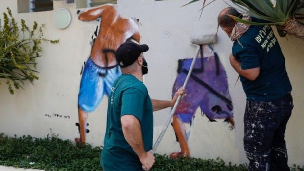 이스라엘 텔아비브 시청 인부들이 해변에 그려진 ‘엿보는 톰’ 벽화를 지우고 있다. 텔아비브 로이터
