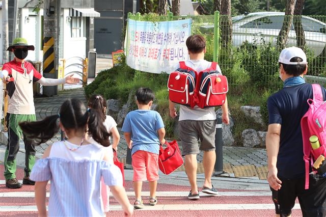 24일 오전 대구의 한 초등학교 앞에서 학부모가 자녀의 가방을 메고 함께 횡단보도를 건너고 있다. 2020.8.24 뉴스1