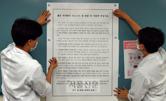 의사들의 총파업을 하루 앞둔 25일 서울 송파구 서울아산병원에서 전공의들이 파업관련 대자보를 병원내에 게시하고 있다. 2020.8.25  박지환 기자 popocar@seoul.co.kr