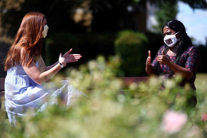 투명 마스크를 쓴 사람들이 수어와 함께 서로의 입 모양을 보며 대화를 하고 있다.  로이터 연합뉴스
