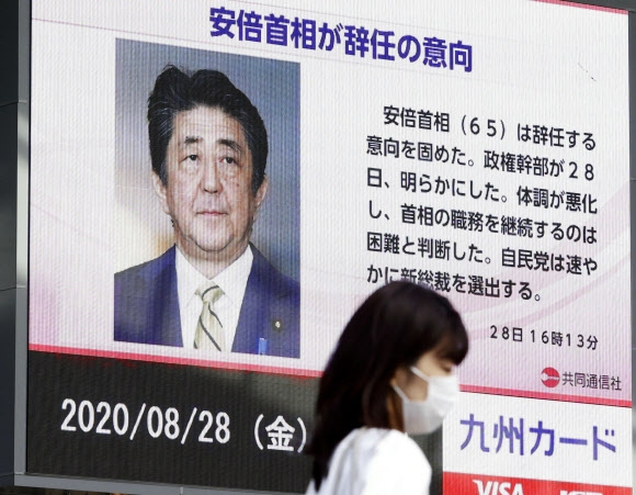 아베 신조 일본 총리가 전격 사임을 발표한 28일 쿠후오카에서 속보를 알리는 뉴스 전광판 앞을 시민이 지나가고 있다. 후쿠오카 AP 연합뉴스