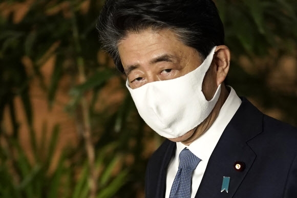 어두운 낯빛의 아베 신조 일본 총리가 28일 전격 사임을 발표한 총리 관저 기자회견 직후 마스크를 쓰고 퇴장하고 있다. 도쿄 AP 연합뉴스