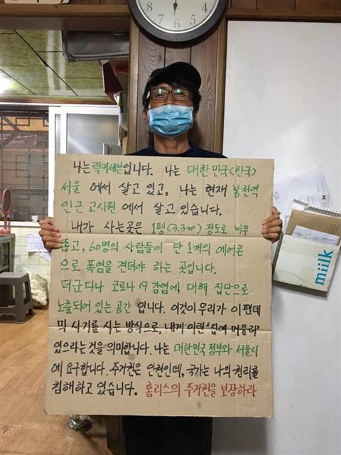 노숙인 활동가 럭키세븐이 서울의 한 고시원에서 ‘주거권을 보장하라’고 적은 피켓을 들고 있는 모습. 빈곤사회연대 제공