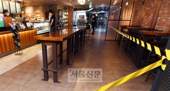 코로나19 재확산 차단을 위한 ‘사회적 거리두기 2.5단계’가 시행된 30일 서울 중구의 한 프랜차이즈형 커피전문점 매장에 테이블에 앉지 못하도록 접근을 차단하는 테이프가 붙어 있다. 박윤슬 기자 seul@seoul.co.kr