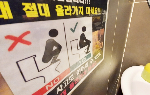 서울의 한 화장실에 좌변기 위에 올라가지 말라는 그림이 붙어 있다. 도준석 기자 pado@seoul.co.kr