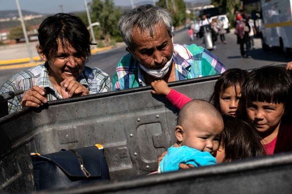 그리스 레스보스섬의 모리아 난민캠프에 수용된 이들이 11일 쓰레기통 안에 앉아 있는 아이들을 돌보고 있다. 유럽연합(EU) 10개국이 나눠 수용하기로 한 미성년 400명은 이들과 달리 부모가 업는 아이들이다. 미텔레네 로이터 연합뉴스