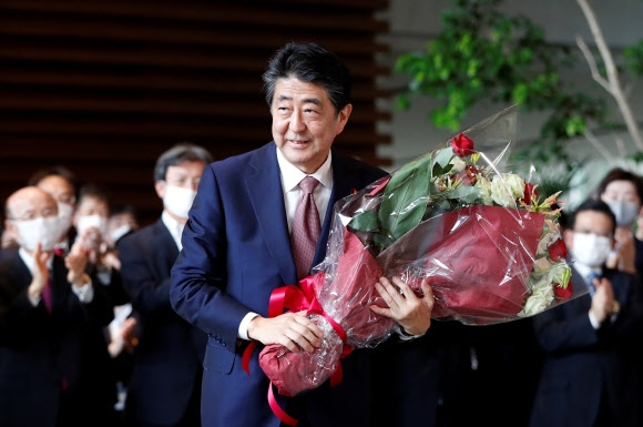 아베 신조 전 일본 총리가 16일(현지시간) 도쿄 총리관저를 떠나며 꽃다발을 받고 있다. 로이터 연합뉴스