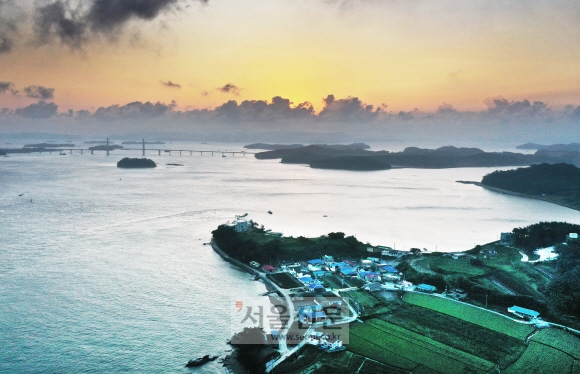 초전마을에서 본 원산도의 해돋이 풍경. 멀리 안면도와 원산도를 잇는 원산안면대교 너머로 해가 뜨고 있다. 그 너머는 충남 보령이다. 섬이 남향인 덕에 같은 자리에서 몸만 돌리면 해넘이 풍경과 만날 수 있다.