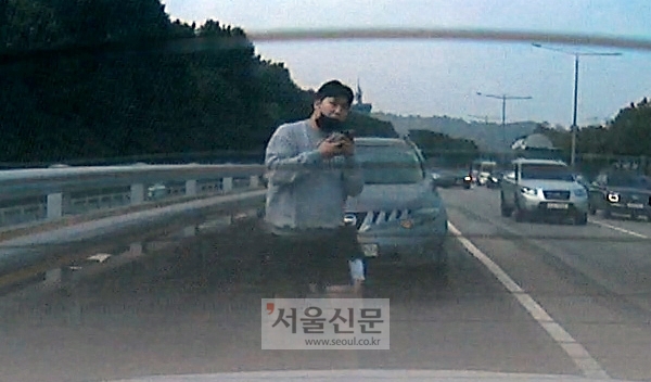 지난 15일 오후 1시쯤 서울 반포동 올림픽대로 갓길에서 고통을 호소하던 여성 운전자를 발견한 정효남씨가 119에 신고전화를 하고 있다. [사진: 독자 제공(김호씨)]