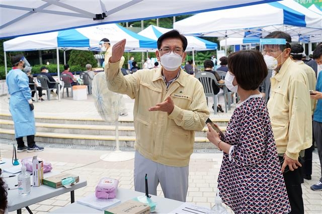 지난달 22일 동대문구청 앞 광장에 설치된 선별진료소를 찾은 유덕열(왼쪽) 구청장이 직원들의 일손을 돕기 위해 구민들에게 검사 절차를 안내하고 있다. 동대문구 제공