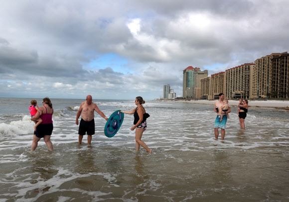 사람들이 17일(현지시간) 미국 플로리다주 오렌지 비치에서 허리케인 샐리가 이 지역을 통과한 지 하루 만에 걸프만 해변에서 물놀이를 즐기고 있다. 게티/AFP 연합뉴스