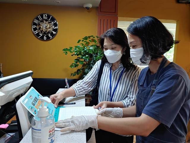 서울 중구 직원(왼쪽)이 지역 내의 한 식당을 방문해 수기 출입명부 가림판 세트를 배부하고 있다. 중구 제공