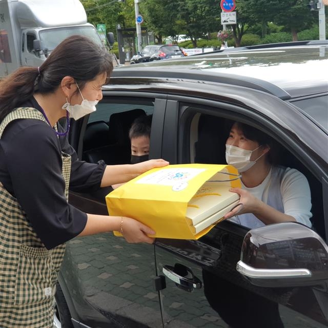 서울 도봉구 한 어린이집 보육교사가 드라이브 스루 방식으로 건강간식 꾸러미를 영유아 부모에게 전달하고 있다. 도봉구 제공