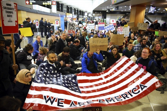 2017년 1월 시애틀 공항에서 여러 인종의 사람들이 모여 “우리는 미국이다”라고 적힌 성조기를 들고 있다. AP