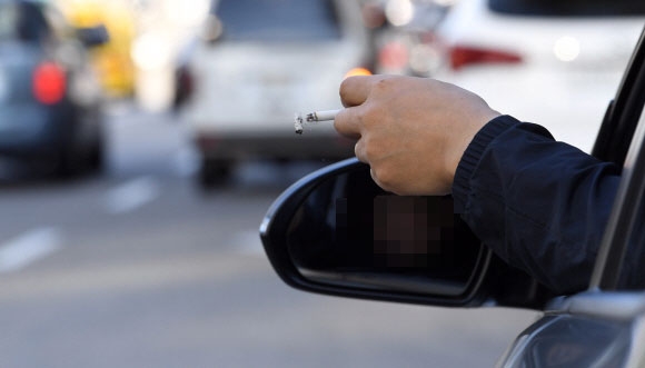 운전 중 흡연 문제를 두고 흡연자와 비흡연자 간의 갈등이 여전하다. 한 운전자가 차량 창문에 팔을 걸친 채 흡연하는 모습. 정연호 기자 tpgod@seoul.co.kr