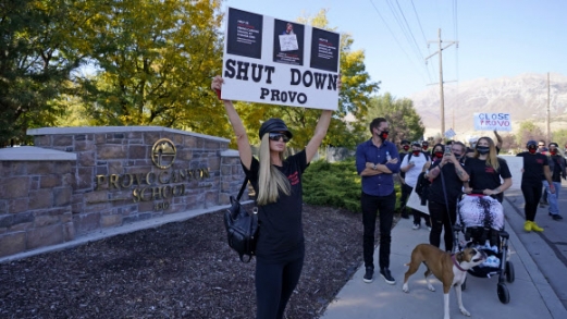 Paris Hilton poses for a photo in front of the Provo Canyon School during a protest Friday, Oct. 9, 2020, in Provo, Utah. Hilton was in Utah Friday to lead a protest outside a boarding school where she alleges she was abused physically and mentally by staff when she was a teenager. Hilton, now 39, went public with the allegations in a new documentary and wants a school that she says left her with nightmares and insomnia for years to be shut down. (AP Photo/Rick Bowmer)