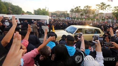 지난 14일 외부 행사 참석차 왕궁을 나와 도심 상업지구로 향하던 수티다 태국 왕비를 태운 자동차가 반정부 시위대 앞을 지나가자 시위대원들이 일제히 세 손가락 경례를 붙이고 있다. 방콕 로이터 연합뉴스