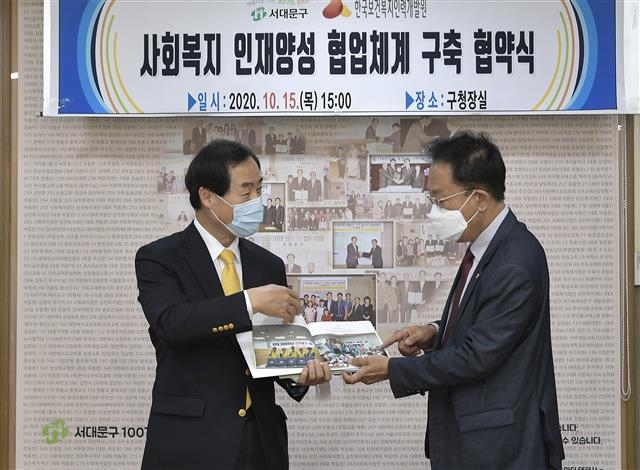 문석진(왼쪽) 서대문구청장이 지난 15일 서울 서대문구청에서 열린 ‘서대문구 사회복지 인재양성 협업 협약식’에서 허선 한국보건복지인력개발원장에게 ‘마봄협의체’ 성과 사례집을 보여 주며 소개하고 있다. 서대문구 제공