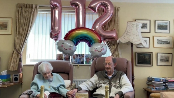 지난 24일(이하 현지시간) 세상을 떠난 영국 최고령 조앤 호콰드(왼쪽) 할머니가 스무살 연하로 말년을 함께 보낸 케네스 베드퍼드와 함께 지난 3월 29일 112번째 생일 축하를 받고 있다. BBC 홈페이지 캡처 