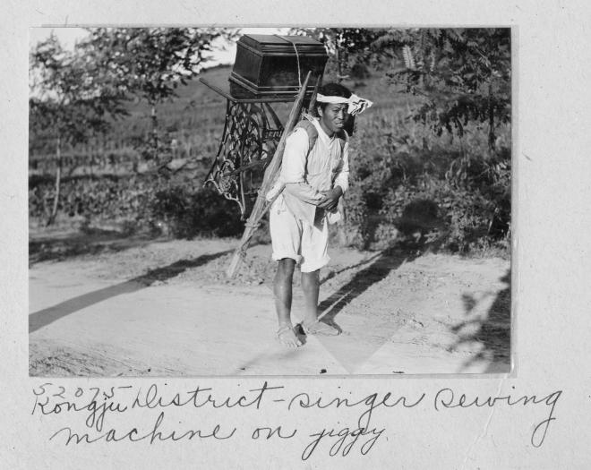 ‘충남인의 100년 전 생활상’ 사진전에 있는 재봉틀을 지고 있는 남자. 충남도역사문화연구원 제공