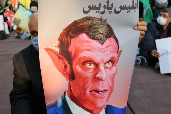 프랑스와 이슬람권의 갈등이 고조되는 가운데 28일(현지시간) 이란 수도 테헤란의 ‘반 프랑스’ 시위대가 에마뉘엘 마크롱 프랑스 대통령을 악마로 묘사한 그림을 들고 있다. 　테헤란 AFP 연합뉴스 
