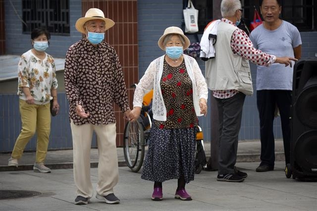 사진은 중국 베이징의 한 공원에서 마스크를 쓴 노부부가 손을 잡고 산책하고 있는 모습. 베이징 AP 연합뉴스