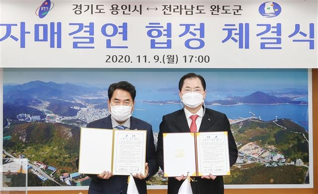백군기(왼쪽) 용인시장과 신우철 완도군수가 9일 완도군청에서 상호 발전·우호 증진을 위한 자매결연을 한 뒤 기념 촬영을 하고 있다. 용인시 제공