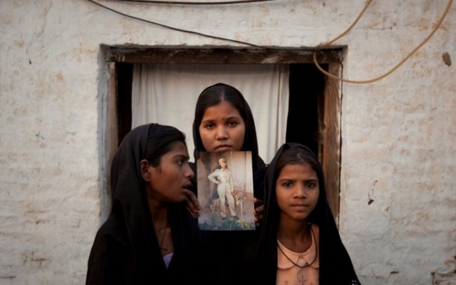 파키스탄 펀잡주에 사는 14세 기독교 소녀의 망명을 영국 정부가 받아들여야 한다는 목소리가 커지고 있다. 이번 사건은 지난해 캐나다로 망명한 아시아 비비 사례를 떠올리게 하는데 딸들이 같은 주 셰이크후푸라에 있는 집 앞에서 어머니의 사진을 들고 촬영에 임하고 있다. 로이터 자료사진 