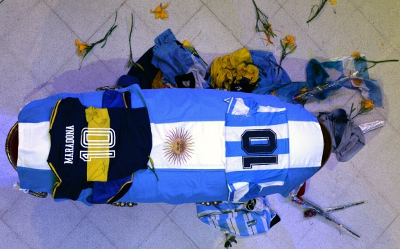 지난 26일(현지시간) 부에노스아이레스의 대통령궁 로사 카사다에 안치된 디에고 마라도나의 관 위와 옆에 팬들이 던진 꽃들과 유니폼들이 다소 어지럽게 눈에 띈다. 아르헨티나 대통령궁 제공 AP 연합뉴스 