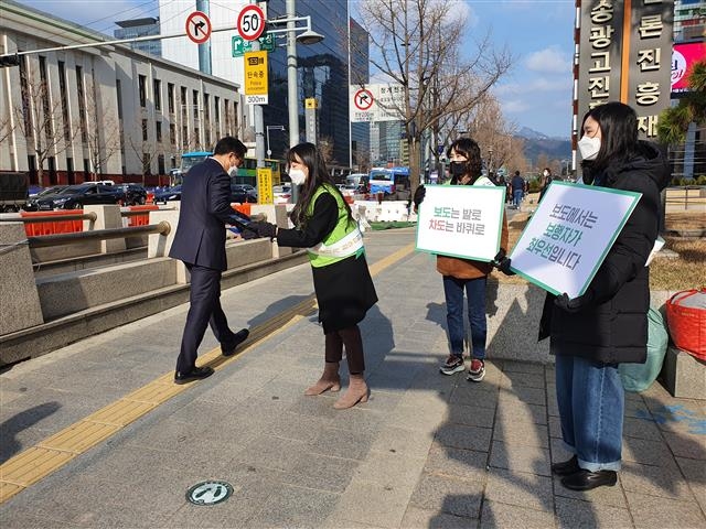 지난 27일 서울 중구 프레스센터 앞에서 서울시와 한국교통안전공단 직원들이 시민들을 상대로 보행안전 메시지를 담은 마스크와 유인물을 나눠 주고 있다. 서울시 제공