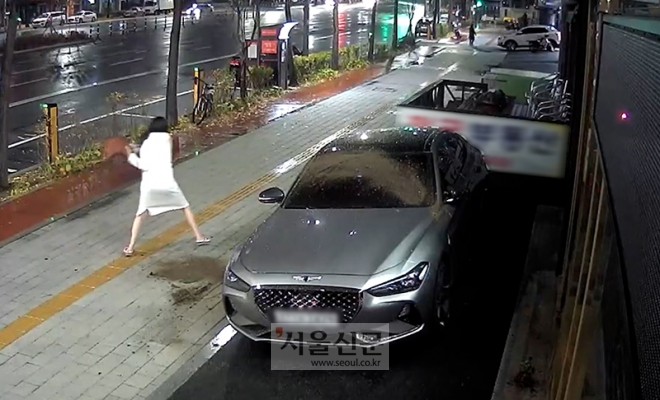 지난 19일 새벽 1시 40분쯤 한 여성이 서울 송파구 석촌역 3번 출구 인근 건물 앞에 주차된 제네시스 차량에 화분을 던지고 있다. [사진=독자제공]