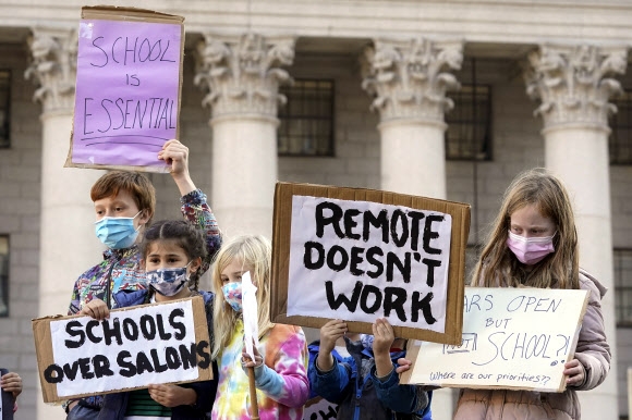 지난 14일(현지시간) 미국 뉴욕시에서 학생들이 시위에 참석해 학교를 개방해달라는 피켓을 들고 있다. AP