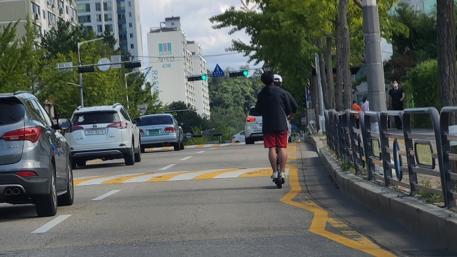 수원시 영통구 한 도로에서 청년 2명이 전동킥보드를 타고 도로를 주행하고 있다. 