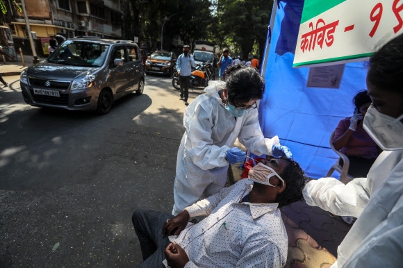 6일(현지시간) 인도 뭄바이의 한 거리에서 의료진들이 코로나19 진단을 위해 한 시민의 검체를 채취하고 있다. 2020.12.6  EPA 연합뉴스