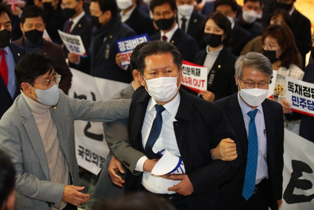 정청래 더불어민주당 의원이 10일 오후 국회 본회의장 앞에서 손피켓을 들고 시위하는 국민의힘 의원들과 말다툼을 하자 의원들이 말리고 있다/연합