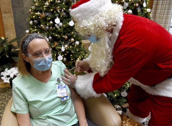 산타 복장을 한 응급전문의가 16일 미국 코넷티컷주 맨체스터 메모리얼병원에서 간호사에게 화이자 백신을 접종하고 있다. 맨체스터 로이터 연합뉴스