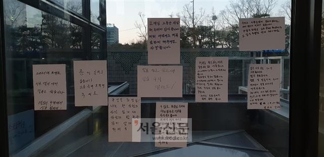 지난 16일 서울 여의도 LG트윈타워 사옥 로비 유리문에 청소노동자들이 작성한 집단해고 철회 선전물이 붙어 있다.