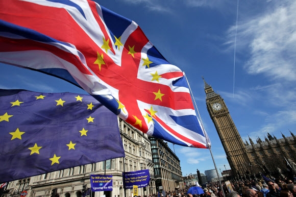 24일(현지시간) 영국와 유럽연합(EU)의 브렉시트 최종 협상이 마무리됐다. 사진은 2017년 브렉시트에 반대하는 시민들이 EU 국기 등을 들고 행진하는 뒤로 영국 국회의사당이 있는 모습.  런던 AFP 연합뉴스