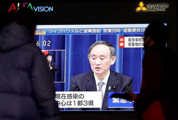 일본에서 코로나19 감염자가 걷잡을 수 없이 증가하고 있는 가운데 7일 스가 요시히데 총리가 앞으로 한 달 동안 도쿄도 등 수도권에 긴급사태를 선포한다고 밝히는 모습을 행인들이 TV를 통해 지켜보고 있다. 도쿄 로이터 연합뉴스