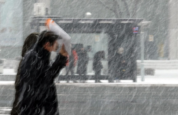 오후 들어 서울 지역에 눈이 내리기 시작한 12일 오후 서울 세종대로에서 시민들이 눈을 맞으며 이동하고 있다. 2021.1.12  연합뉴스