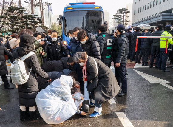 16개월 된 입양 딸 정인이를 학대해 숨지게 한 혐의를 받고 있는 양부모에 대한 첫 공판이 열린 13일 오전 서울 양천구 남부지방법원에서 양모 장씨가 탄 호송차량이 법원을 나서자, 한 시민이 분노하며 바닥에 누워 살인죄 처벌을 요구하고 있다. 2021. 1. 13 <br>오장환 기자 5zzang@seoul.co.kr