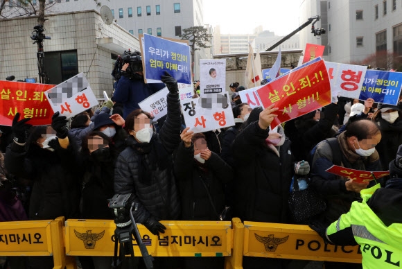 16개월 된 입양 딸 정인 양을 학대해 숨지게 한 혐의를 받는 양부모의 첫 재판이 열린 13일 서울남부지법에서 양모가 탄 호송차가 법원을 빠져나가자 시민들이 항의하고 있다. 2021.1.13 연합뉴스