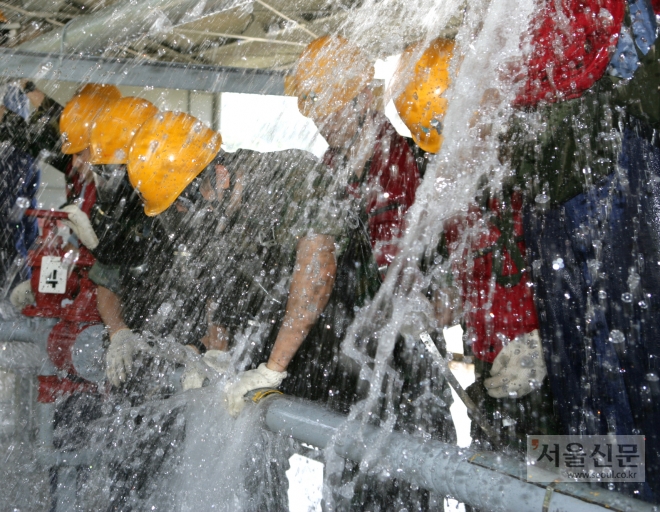 소화방수훈련에 참가한 해군 대원들이 온 몸으로 쏟아져 나오는 물을 막고 있다. 해군 제공